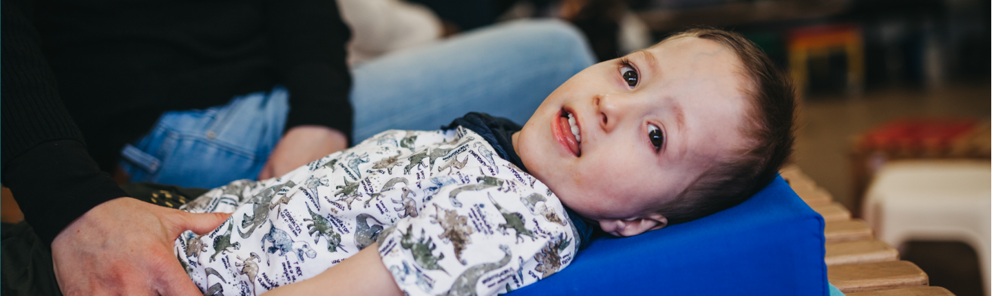 Young boy smiling and laying down on his back.