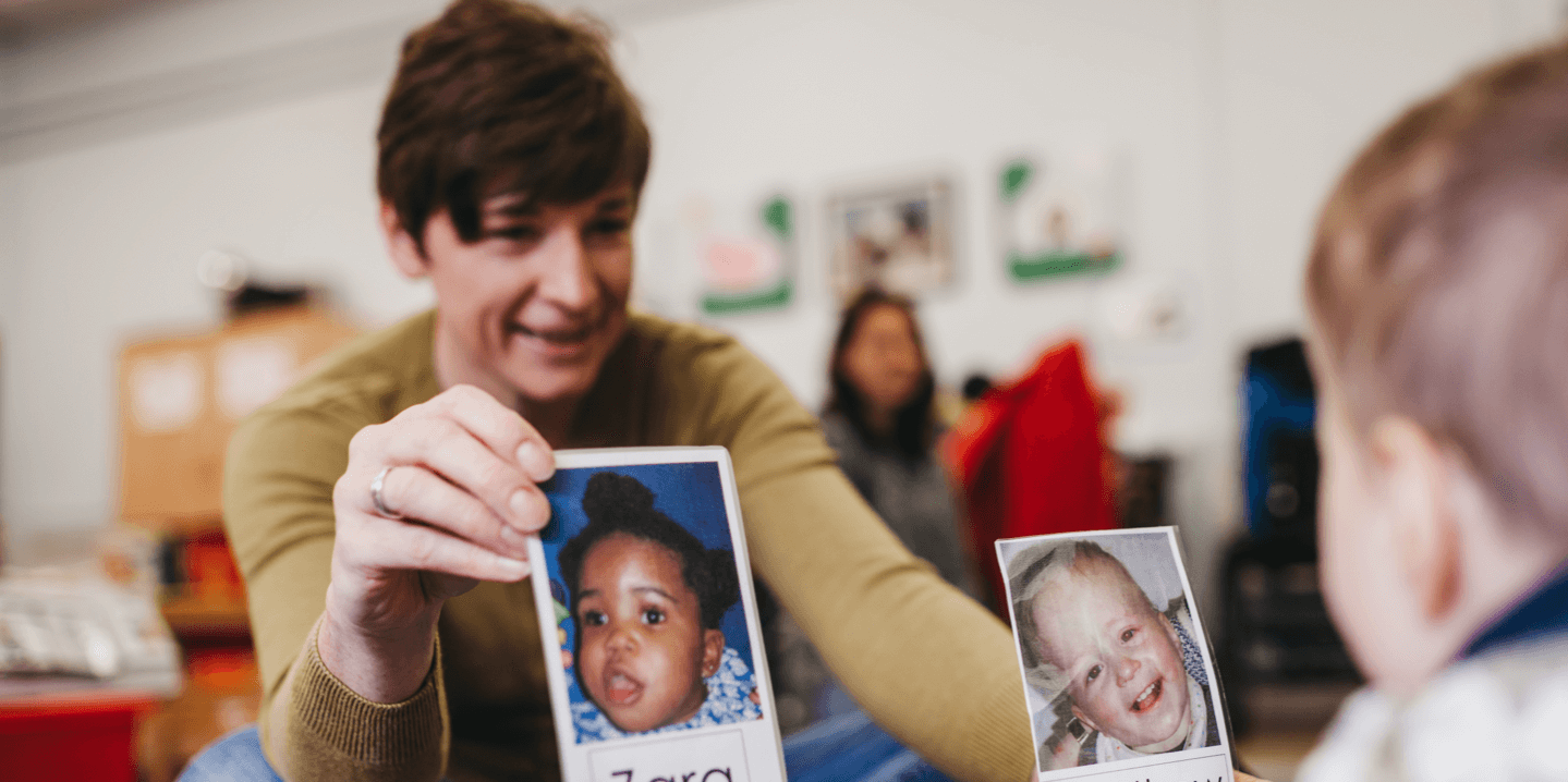 A child looking at 2 images of children's faces on polaroid pictures.