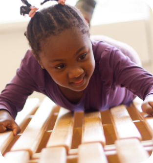 A girl playing on some wooden slats.